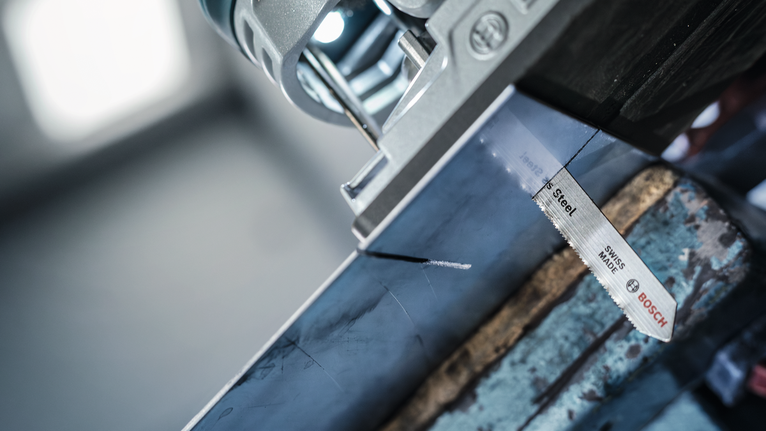 Gergaji ukir memotong balok logam yang ditandai di bengkel.