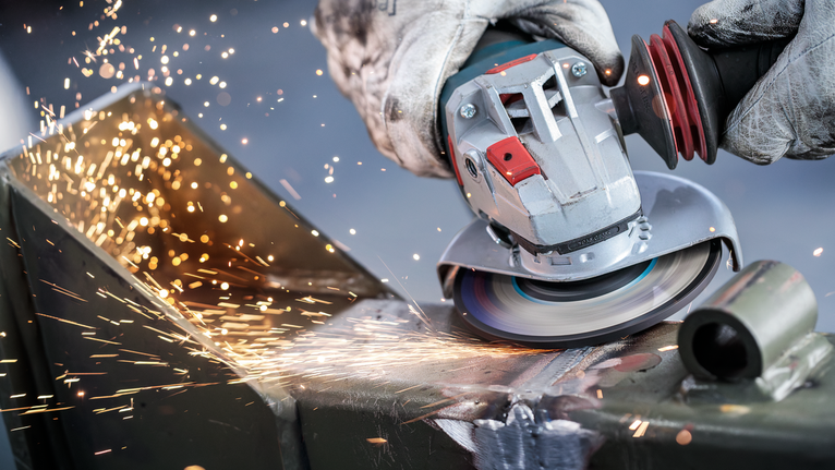 Mata Gerinda Potong Berikat PRO Metal, 125 x 6 x 22,23 mm, X-Lock Orang yang mengenakan peralatan keselamatan menggiling logam, menghasilkan percikan terang.
