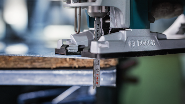 Gergaji ukir memotong sepotong kayu di meja kerja.