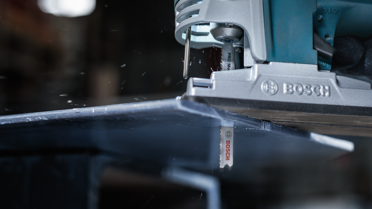 Gergaji ukir memotong lembaran logam di bengkel.