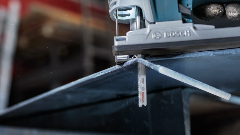 Gergaji ukir memotong lembaran logam sepanjang garis yang ditandai.