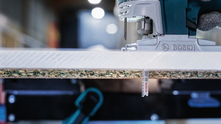 Gergaji ukir bertenaga listrik untuk memotong sepotong kayu laminasi.