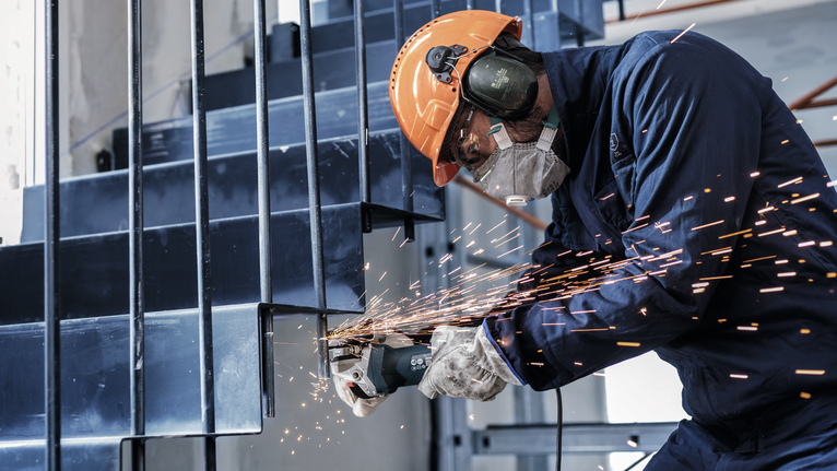 Orang yang mengenakan peralatan keselamatan menggesek tangga logam, sehingga menimbulkan percikan api ke luar.