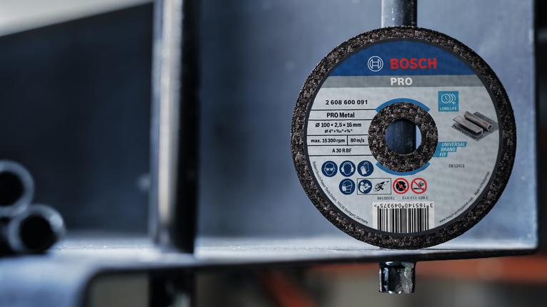 Cakram pengasah yang dipasang pada struktur logam dalam lingkungan industri.