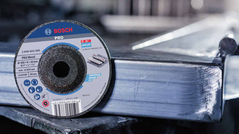 Cakram pemotong ditempatkan pada balok logam mengilap di ruang kerja industri.