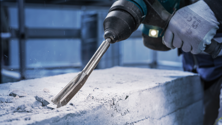 Chisel PRO SDS plus Hollow Gouging, 22 x 250 mm Orang yang mengenakan peralatan keselamatan memahat beton dengan palu putar.