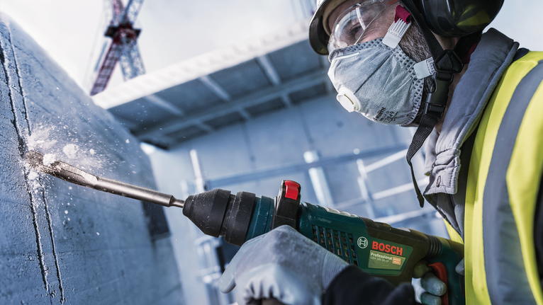 Chisel PRO SDS plus Hollow Gouging, 22 x 250 mm Seseorang yang mengenakan peralatan keselamatan mengebor beton di lokasi konstruksi.