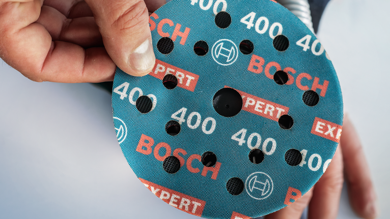 Seseorang menempatkan cakram pengamplasan abrasif bundar ke sebuah alat.