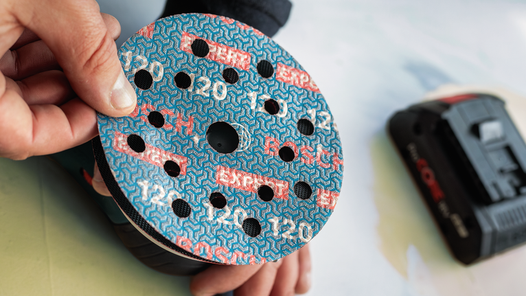 Seseorang memasang cakram pengamplas ke mesin pengamplas listrik.