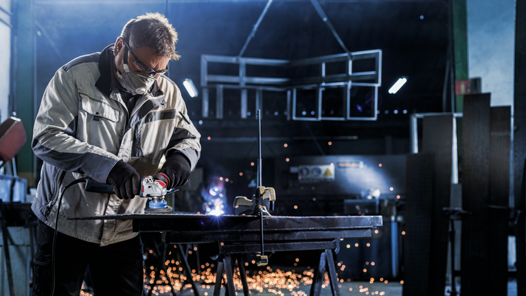 Sikat Mangkuk PRO Stainless Steel heavy X-Lock, 75 x 0,5 mm Seseorang yang mengenakan peralatan keselamatan menggiling logam di meja kerja dengan percikan api yang beterbangan.