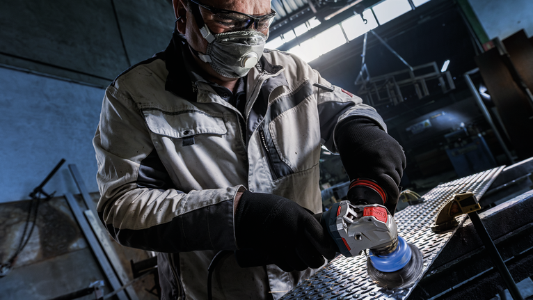Sikat Mangkuk PRO Stainless Steel heavy X-Lock, 75 x 0,5 mm Orang yang mengenakan peralatan keselamatan memoles lembaran logam dengan alat listrik.