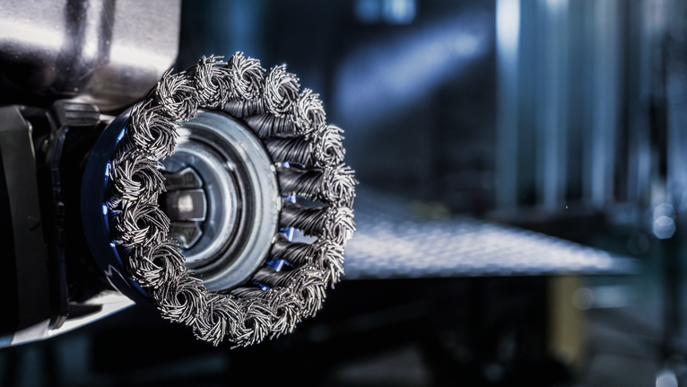 Tampilan dekat pemasangan roda sikat kawat pada perkakas listrik di bengkel.