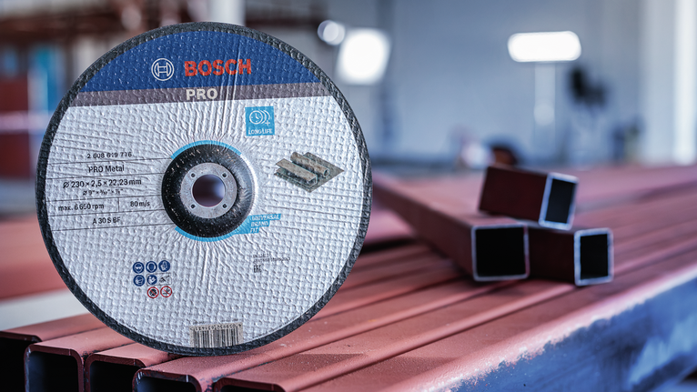 Cakram pemotong berdiri tegak di atas balok logam di bengkel.