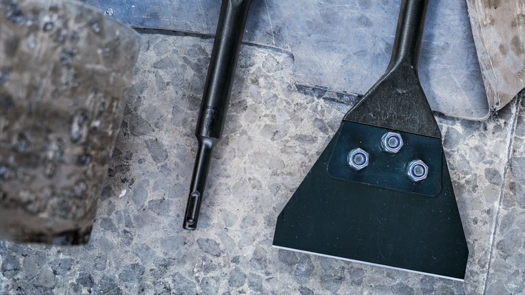 Peralatan dan perkakas pahat di lantai batu, di samping palu yang sudah usang.