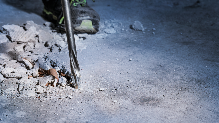Mata bor memecahkan beton di lokasi konstruksi.