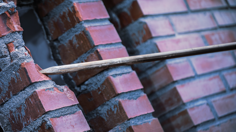 Pahat runcing menembus dinding bata merah.