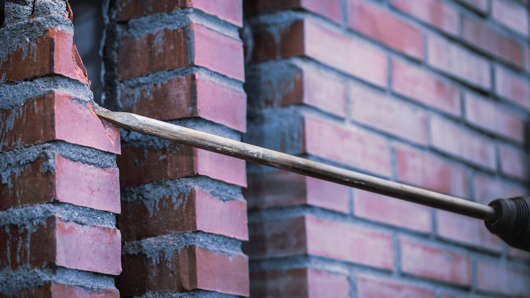 Mata bor membuat lubang pada dinding bata.