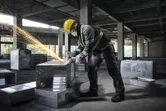 Seseorang yang mengenakan peralatan keselamatan menggesek saluran logam, sehingga menimbulkan percikan api.