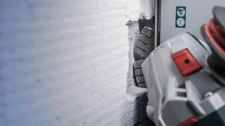 Wall chaser memotong alur lurus ke dalam dinding beton.