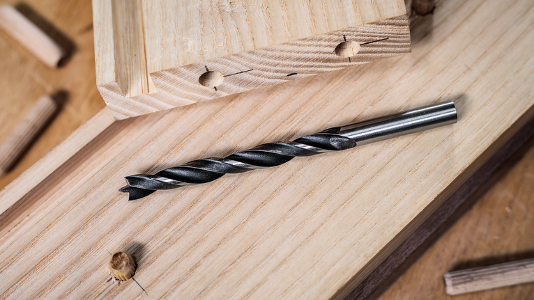 Mata bor putar tergeletak di papan kayu di ruang kerja pertukangan.