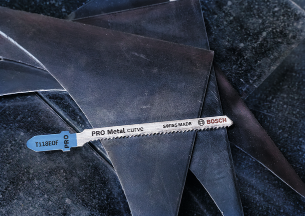 Mata gergaji ukir logam diletakkan pada potongan-potongan lembaran logam yang ditumpuk.