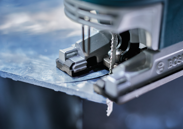 Gergaji ukir memotong lembaran logam.