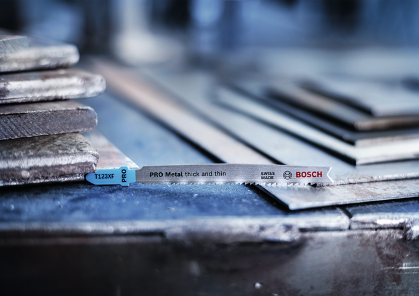 Mata gergaji ukir diletakkan pada tumpukan lembaran logam di bengkel.