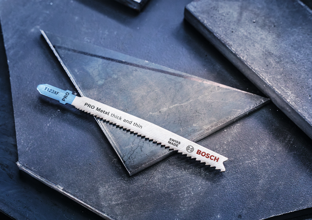 Mata gergaji logam diletakkan pada lembaran logam berwarna gelap.