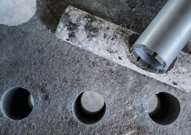 Mata bor inti di samping sampel inti beton dan tiga lubang bor.