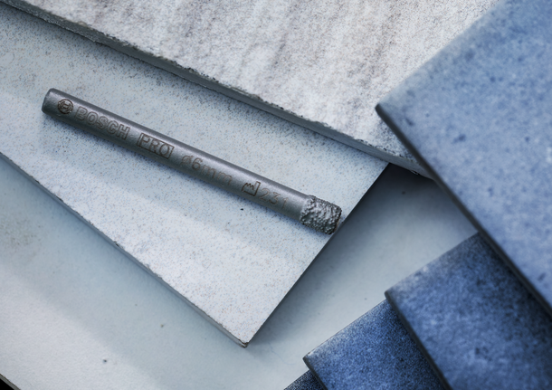 Mata bor diletakkan di atas tumpukan ubin keramik.