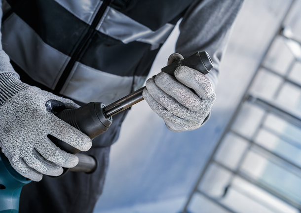 Orang yang mengenakan perlengkapan keselamatan memasang sedikit logam pada perkakas listrik.