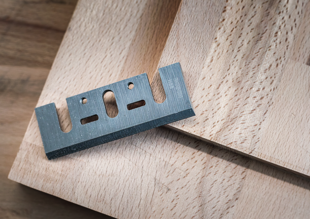 Pisau pemotong logam diletakkan pada papan kayu.