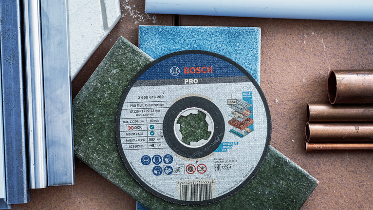 Cakram pemotong ditempatkan pada ubin berwarna, dikelilingi pipa logam dan plastik.