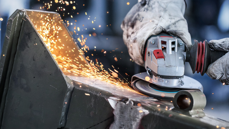 Mata Gerinda Potong Berikat PRO Metal, 125 x 6 x 22,23 mm, X-Lock Orang yang mengenakan peralatan keselamatan menggiling logam dengan penggiling sudut, menghasilkan percikan api.