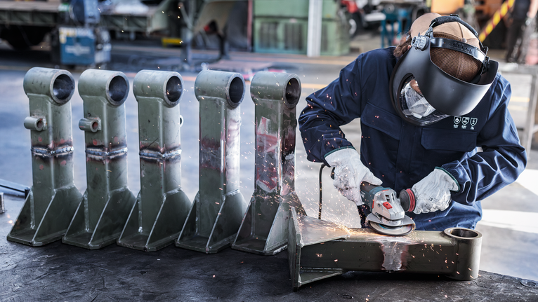 Mata Gerinda Potong Berikat PRO Metal, 125 x 6 x 22,23 mm, X-Lock Orang yang mengenakan peralatan keselamatan menggiling bagian logam, sehingga menimbulkan percikan api di bengkel.