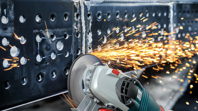 Penggiling sudut memotong balok logam saat percikan api beterbangan.