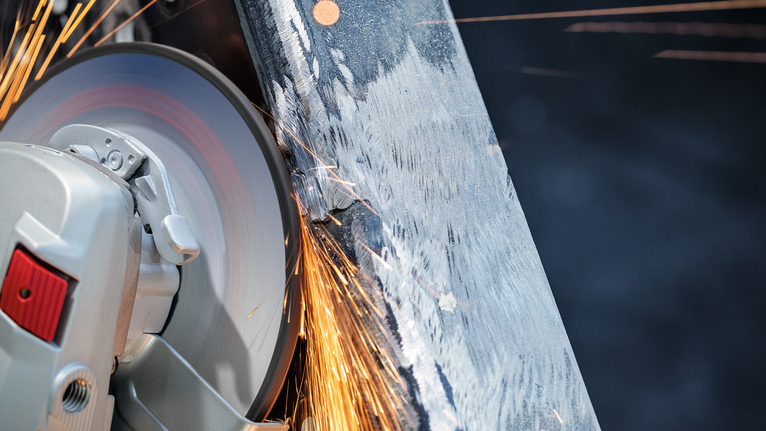 Roda pemotong menghasilkan percikan api saat memotong balok logam.