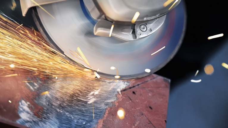 Penggiling sudut memotong logam, menghasilkan percikan terang.