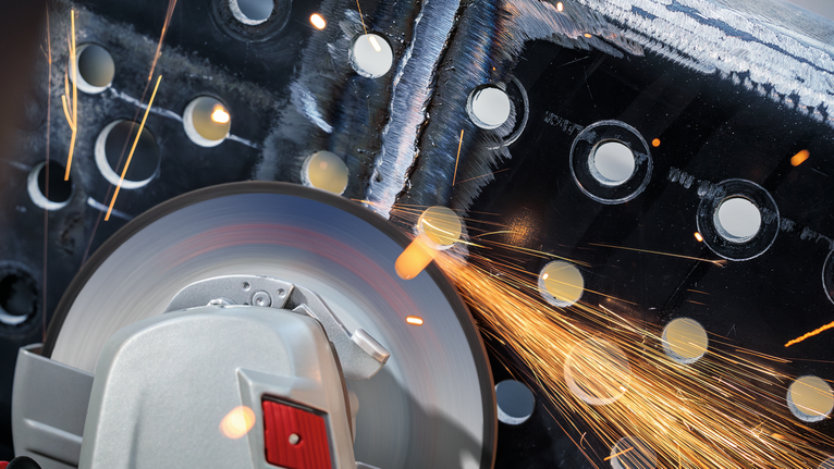 Alat pemotong bergesekan dengan logam yang berlubang, percikan api beterbangan.