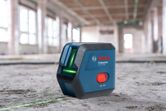 Alat perataan laser yang memproyeksikan garis hijau pada lantai beton di lokasi konstruksi.