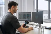 Seseorang menganalisis gambar termal pada monitor ganda menggunakan kamera termal di meja.