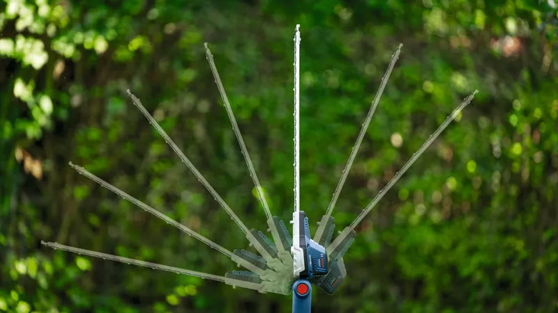 Pemotong pagar teleskopik tanpa kabel yang menunjukkan sudut pemotongan yang dapat disesuaikan di luar ruangan.