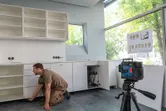 Orang yang memasang lemari dapur menggunakan alat perata laser pada tripod untuk penyelarasan.
