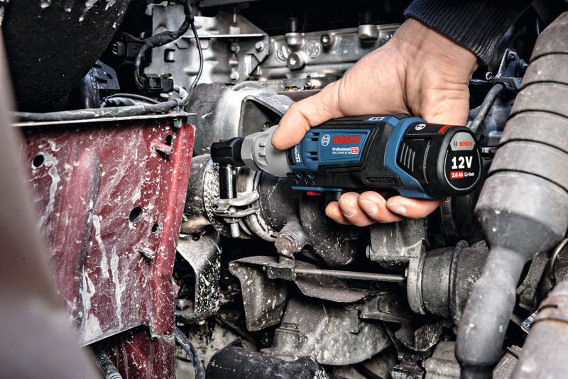 Seseorang menggunakan kunci pas ratchet tanpa kabel untuk mengencangkan baut pada mesin.