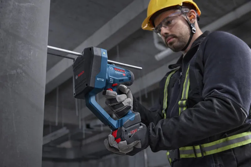 Seseorang yang mengenakan peralatan keselamatan memotong batang berulir dengan pemotong batang tanpa kabel.