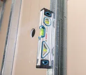 Alat pengukur level untuk mengukur keselarasan terhadap dinding rangka logam.