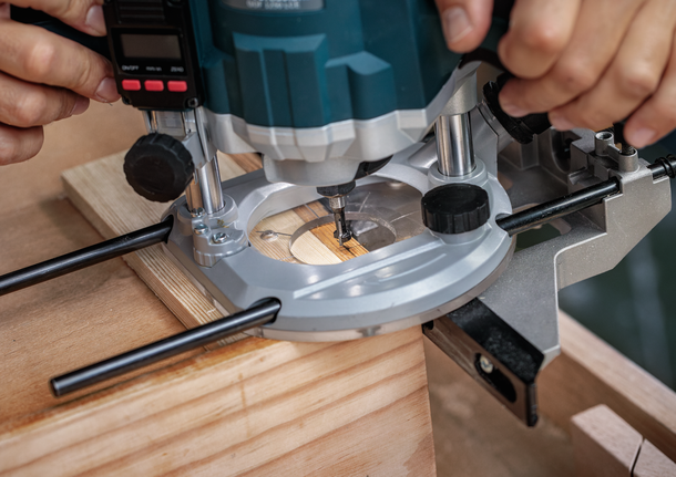 Seseorang menggunakan router terjun untuk memotong alur pada sepotong kayu.