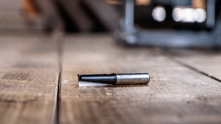 Mata router terletak pada permukaan kayu di bengkel.