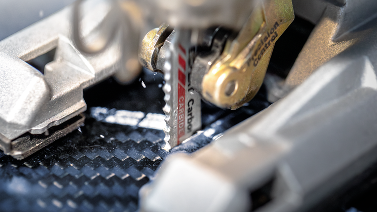 Mata gergaji ukir memotong lembaran serat karbon.