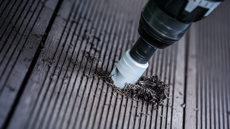 Mesin bor lubang (hole saw) mengebor lubang pada permukaan dek kayu.